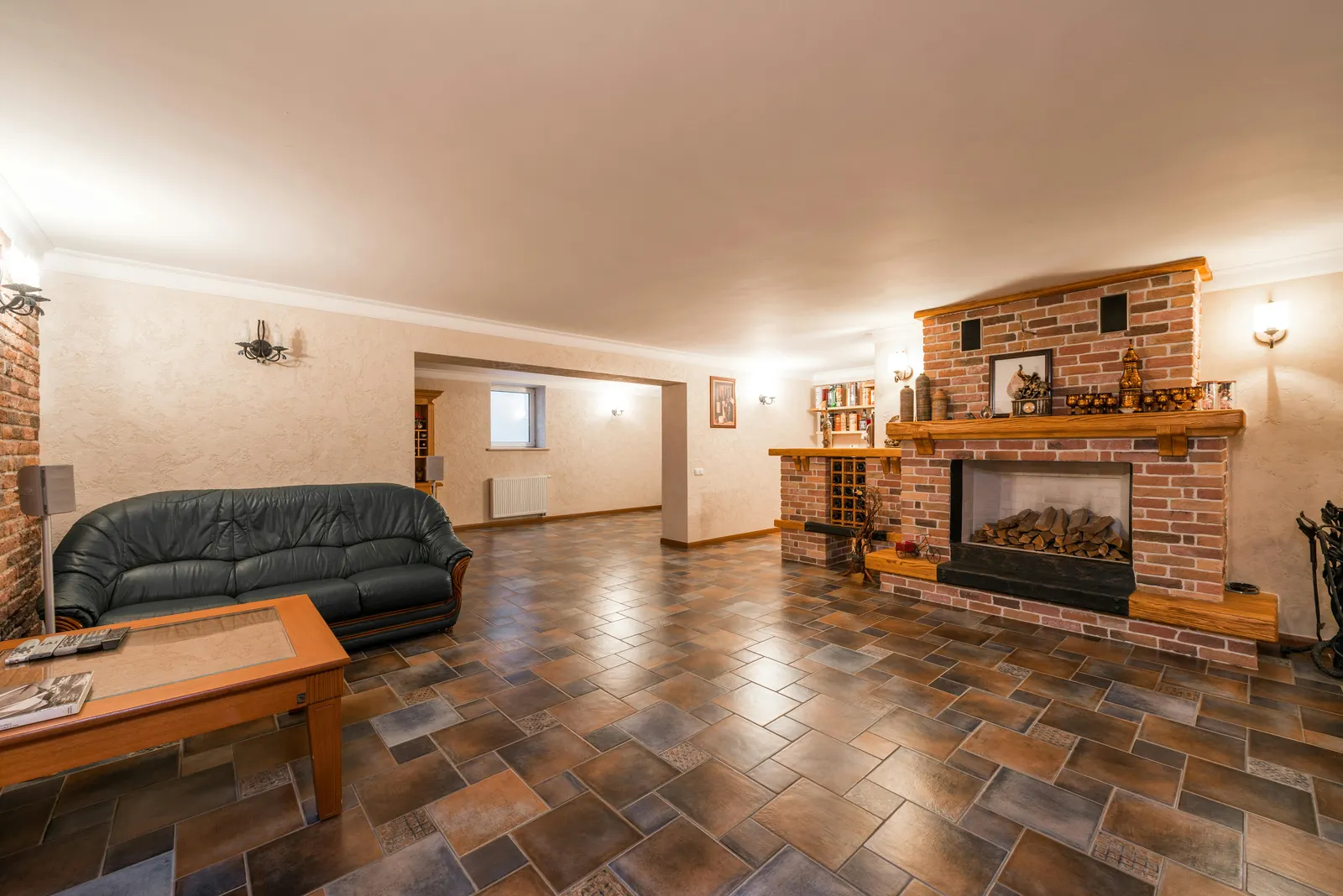 Basement living room with brick fireplace and tile floor