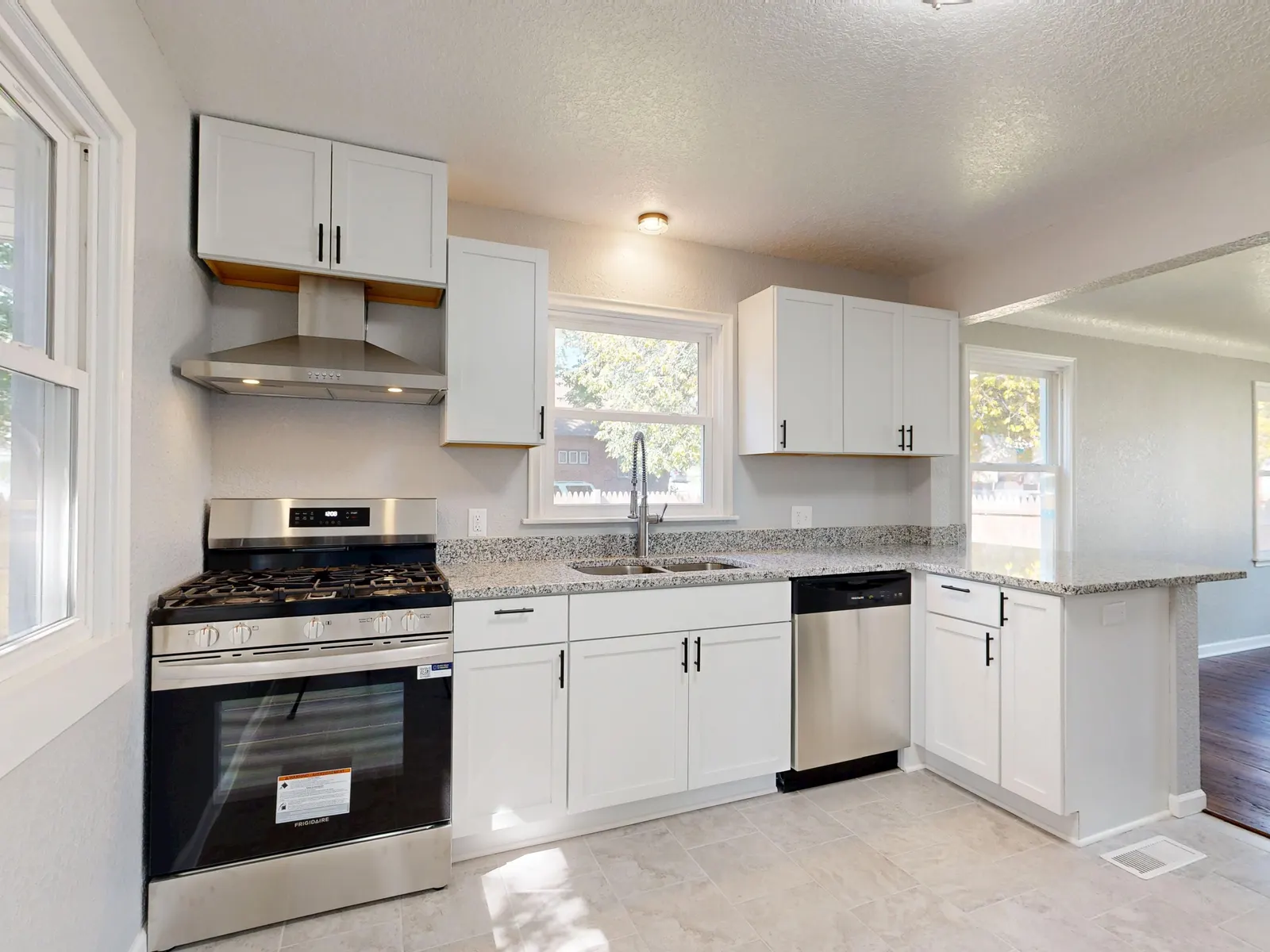 White shaker kitchen with gas range, granite counters and stainless appliances